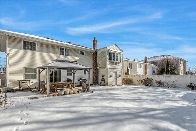 snow covered back of property with a gazebo