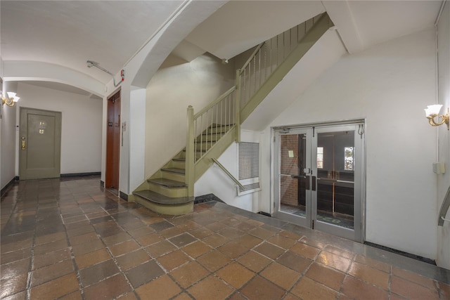 stairs with brick ceiling, lofted ceiling, a chandelier, and french doors