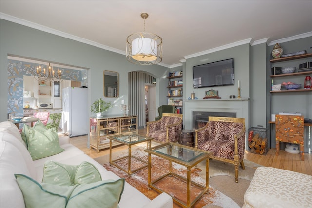 living room featuring crown molding, an inviting chandelier, and light hardwood / wood-style flooring