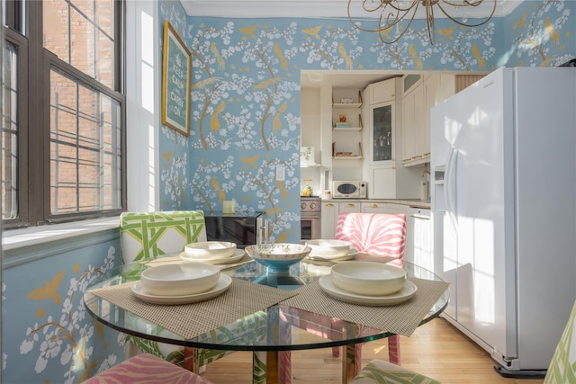 dining area featuring a healthy amount of sunlight, sink, a notable chandelier, and light hardwood / wood-style floors