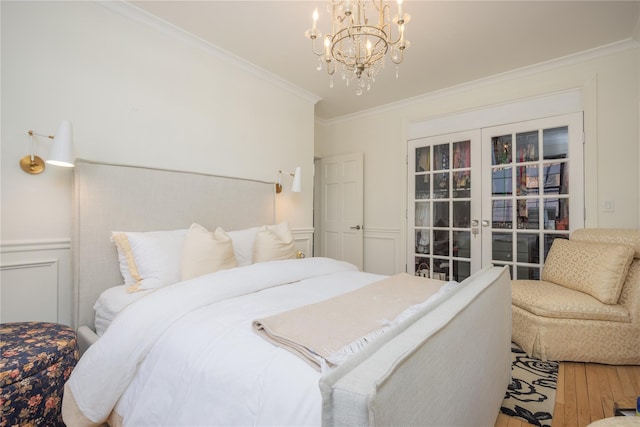 bedroom with french doors, ornamental molding, a chandelier, and hardwood / wood-style flooring