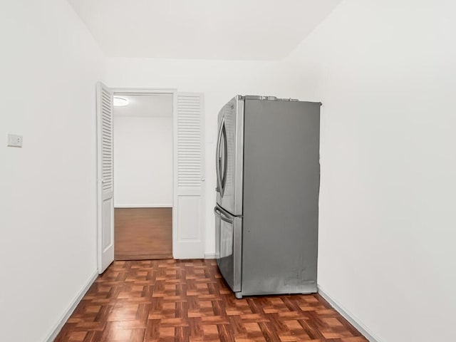 laundry area featuring dark parquet flooring and stacked washer and clothes dryer