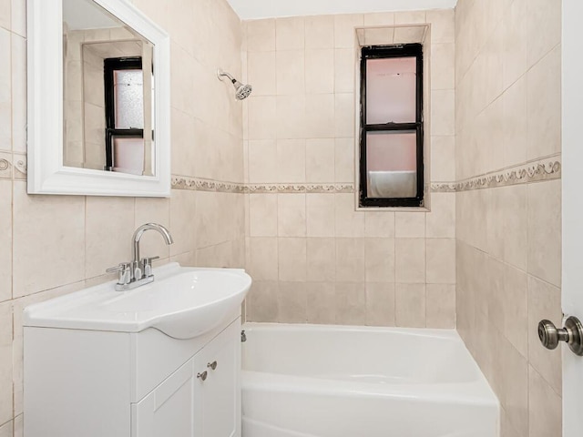 bathroom featuring tile walls, vanity, and tiled shower / bath combo