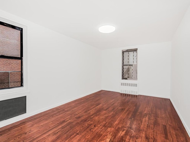 spare room featuring radiator and dark hardwood / wood-style flooring