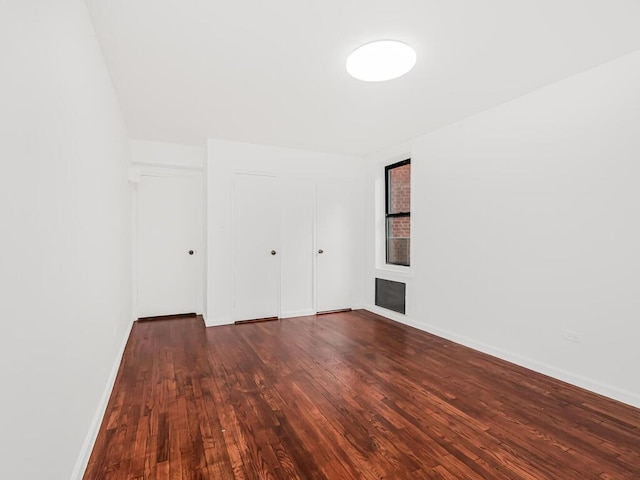 unfurnished bedroom with a brick fireplace and dark hardwood / wood-style floors