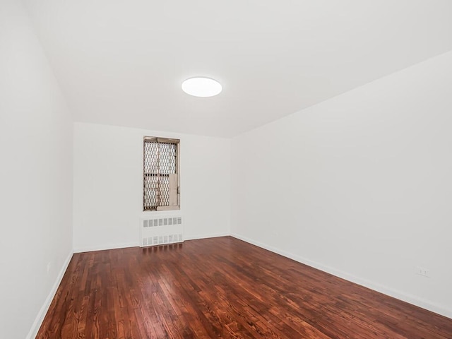 spare room featuring wood-type flooring and radiator heating unit