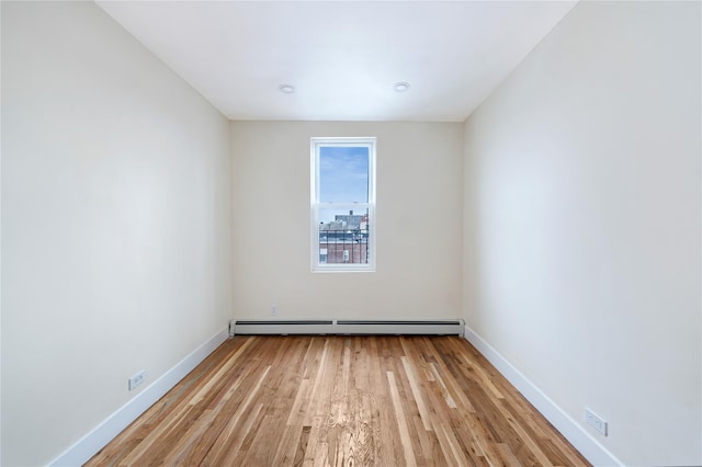 unfurnished room featuring light wood-type flooring and a baseboard heating unit