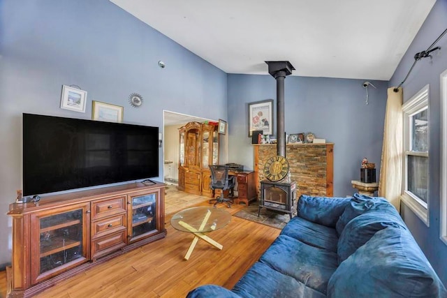 living room with lofted ceiling, light wood-type flooring, and a wood stove