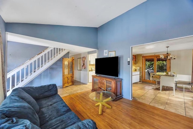 living room with a notable chandelier, vaulted ceiling, and light tile patterned flooring