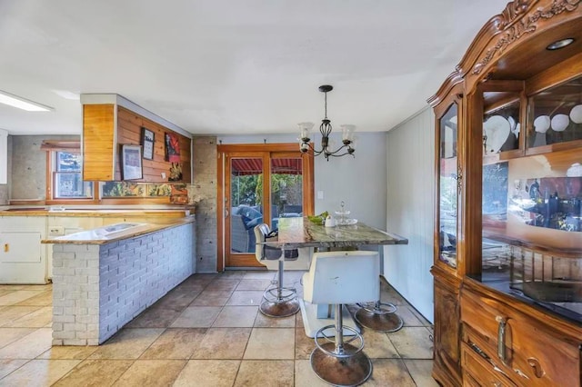 kitchen with hanging light fixtures, a healthy amount of sunlight, a breakfast bar area, and a chandelier