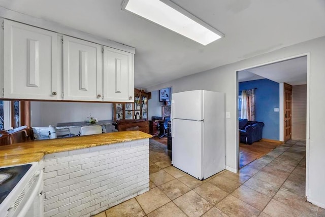 kitchen featuring white appliances, light tile patterned floors, and white cabinets