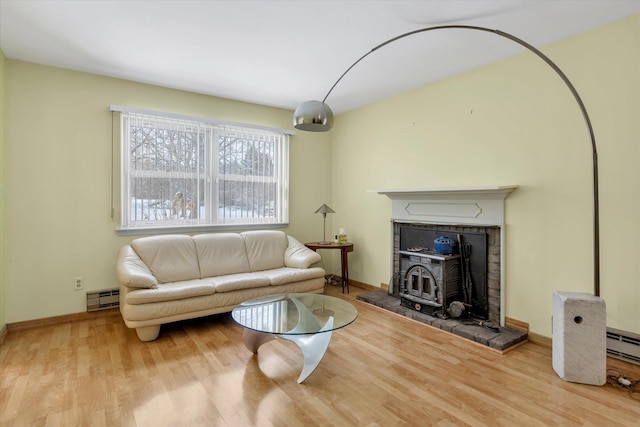 living room with a baseboard radiator, a wood stove, and light hardwood / wood-style flooring