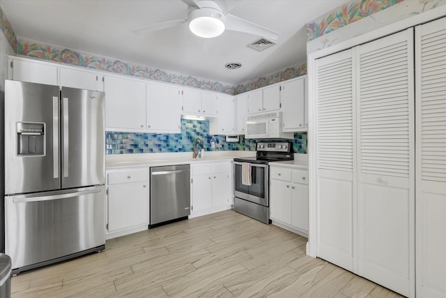 kitchen with sink, ceiling fan, backsplash, stainless steel appliances, and white cabinets