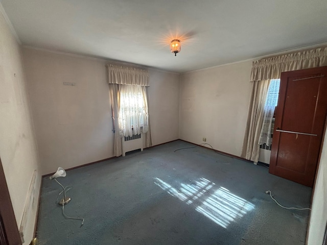 spare room featuring carpet floors, crown molding, and radiator heating unit