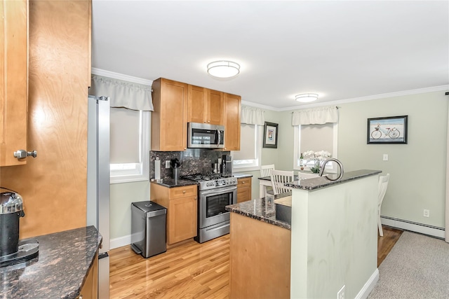 kitchen with a baseboard heating unit, stainless steel appliances, dark stone counters, tasteful backsplash, and ornamental molding