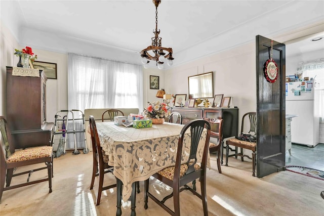 dining space with light colored carpet and a notable chandelier