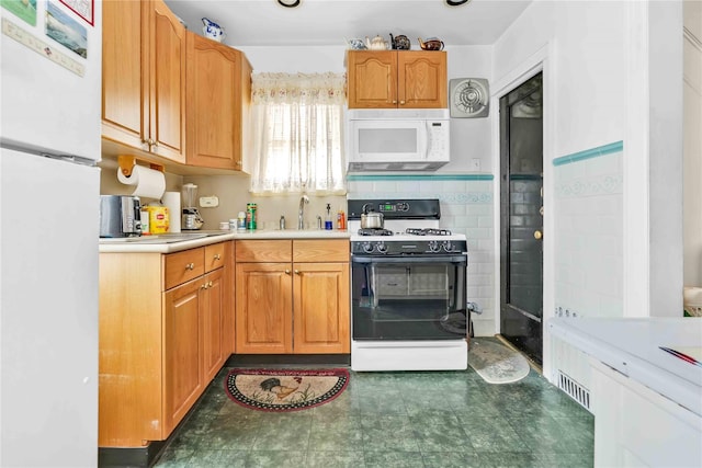 kitchen featuring sink, white appliances, and tasteful backsplash