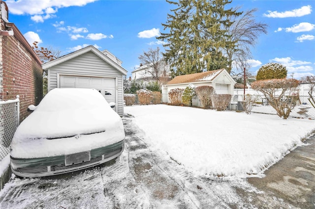 snowy yard featuring an outbuilding and a garage