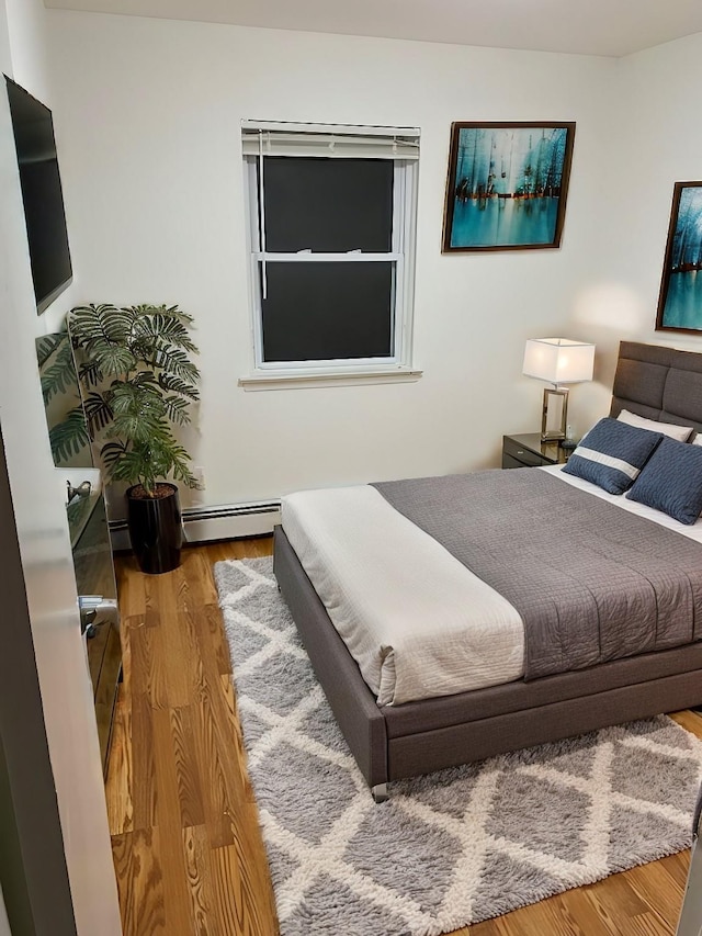 bedroom with hardwood / wood-style floors and baseboard heating