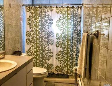 bathroom featuring vanity, curtained shower, and tile walls