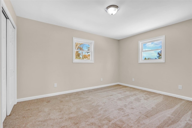 unfurnished bedroom with light colored carpet and a closet