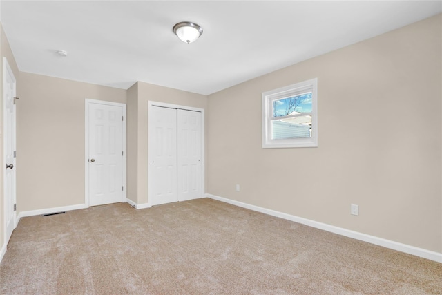 unfurnished bedroom featuring light carpet and a closet