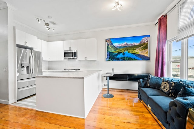 kitchen with crown molding, appliances with stainless steel finishes, white cabinets, and light wood-type flooring