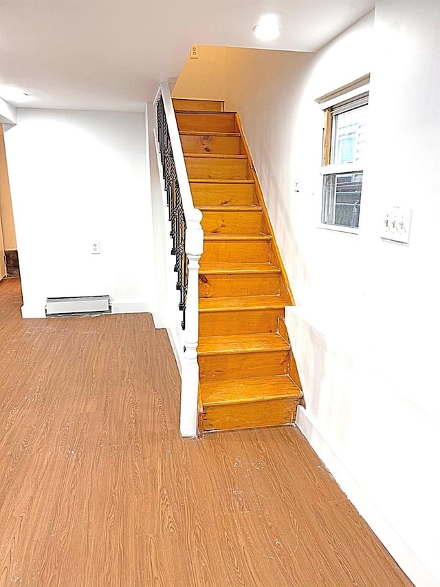 stairs with a baseboard heating unit and hardwood / wood-style floors