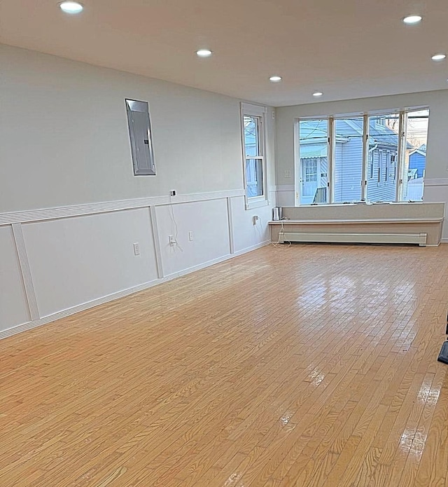 spare room with a baseboard radiator, electric panel, and light wood-type flooring