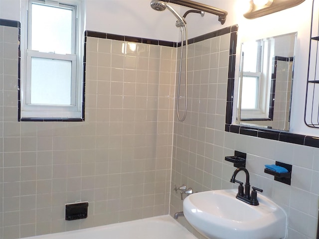 bathroom with a healthy amount of sunlight, tiled shower / bath, tasteful backsplash, and sink