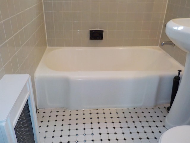 bathroom with a tub, tile walls, and toilet