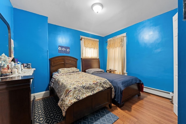 bedroom featuring a baseboard heating unit and light hardwood / wood-style floors