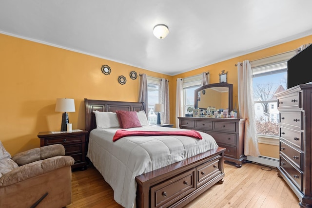 bedroom featuring baseboard heating, crown molding, and light hardwood / wood-style floors