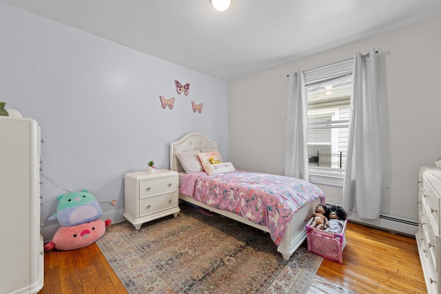 bedroom with a baseboard heating unit and light hardwood / wood-style flooring