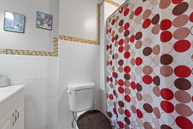 bathroom with vanity, toilet, a shower with shower curtain, and tile walls