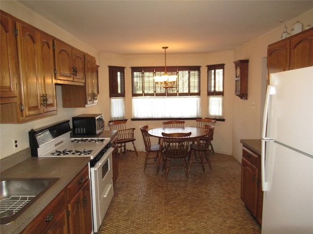 kitchen with hanging light fixtures, white appliances, sink, and a chandelier