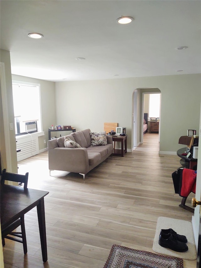 living room with cooling unit, light hardwood / wood-style flooring, and a healthy amount of sunlight