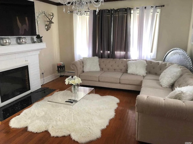 living room featuring a brick fireplace, a baseboard heating unit, dark hardwood / wood-style floors, and a notable chandelier