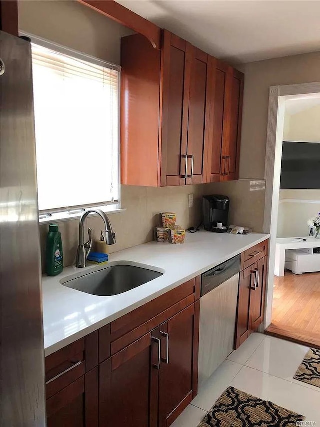 kitchen featuring light tile patterned floors, sink, and stainless steel dishwasher