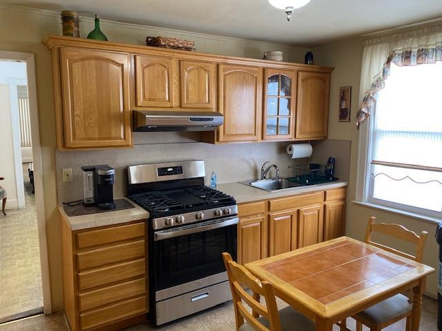 kitchen featuring light tile patterned floors, sink, stainless steel range with gas cooktop, and crown molding