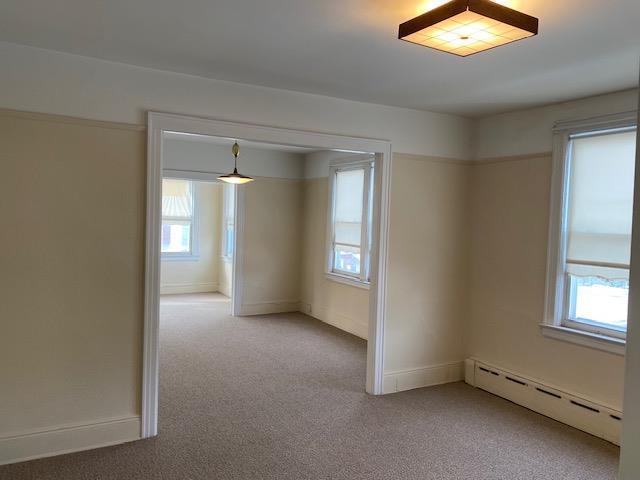 carpeted spare room with a baseboard radiator