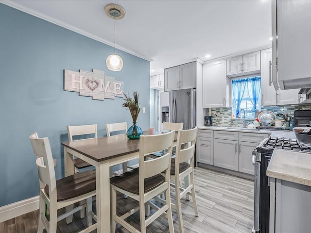 kitchen with light hardwood / wood-style flooring, stainless steel appliances, backsplash, hanging light fixtures, and gray cabinetry