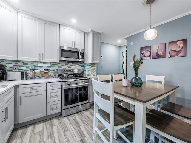 kitchen with pendant lighting, stainless steel appliances, backsplash, light hardwood / wood-style flooring, and crown molding