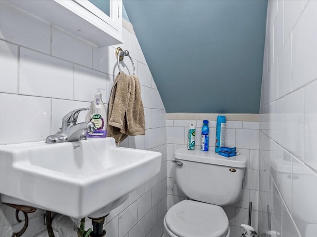 bathroom with lofted ceiling, sink, tile walls, and toilet