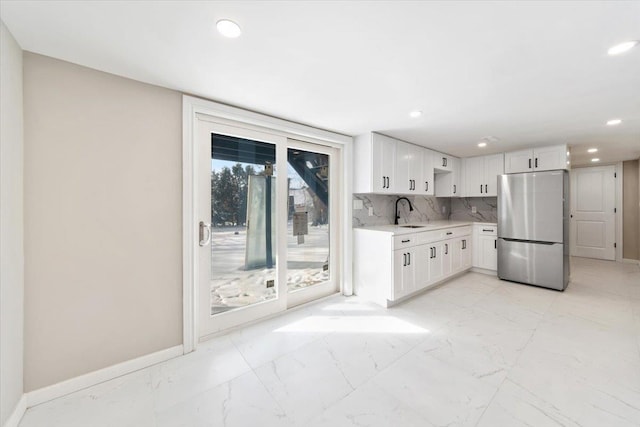 kitchen featuring stainless steel refrigerator, tasteful backsplash, white cabinetry, sink, and a healthy amount of sunlight