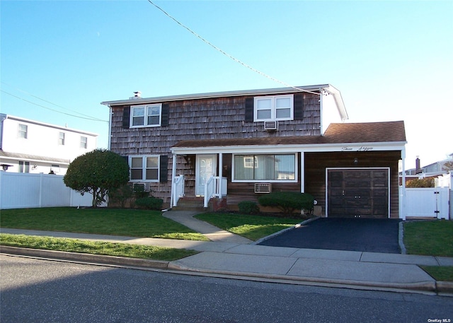 view of front of house with a garage, cooling unit, and a front lawn