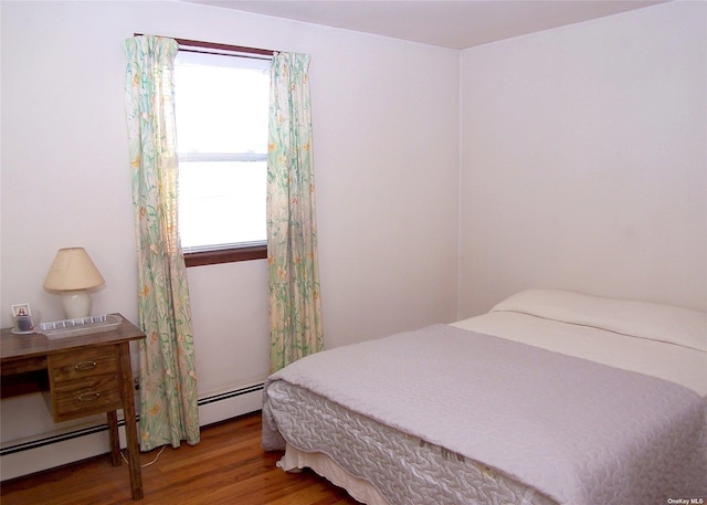 bedroom featuring baseboard heating and hardwood / wood-style flooring