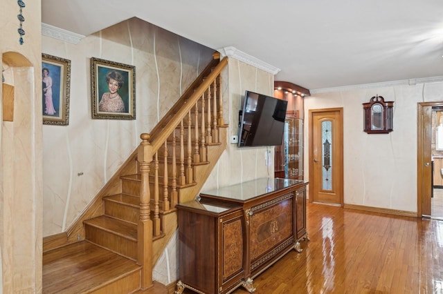 stairs featuring crown molding and hardwood / wood-style flooring