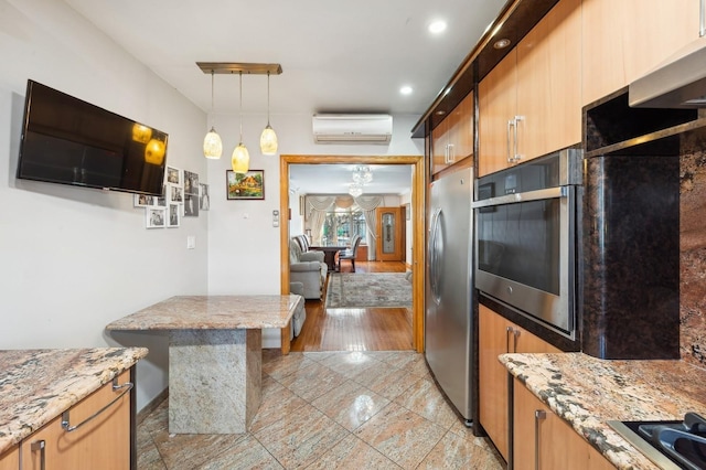 kitchen featuring pendant lighting, stainless steel appliances, light stone counters, and a wall unit AC