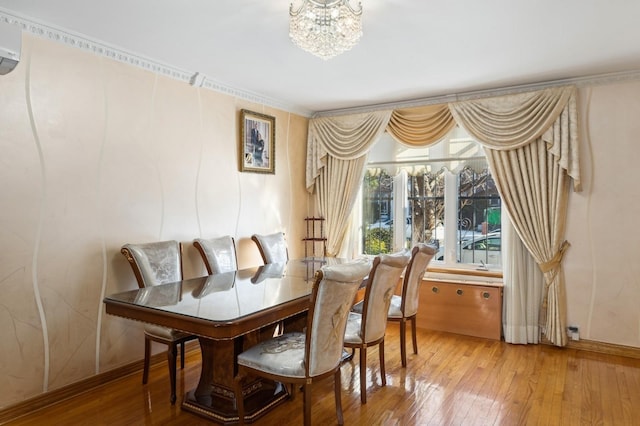 dining area with crown molding, a wall mounted AC, wood-type flooring, and a chandelier